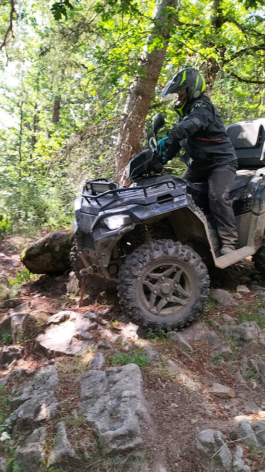 Quad franchissant un passage rocheux sur un sentier forestier